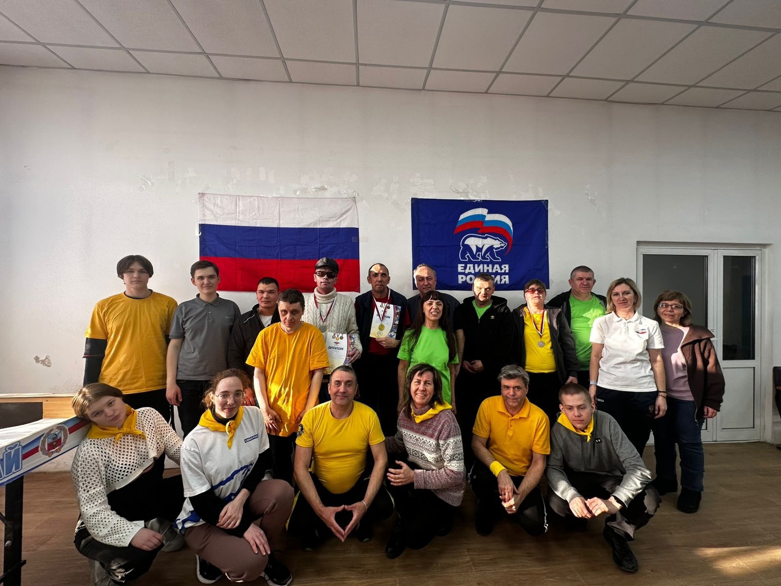 Тифлокомментарий к фотографии: групповая фотография участников Чемпионата на фоне Флага России и флага партии Единая Россия